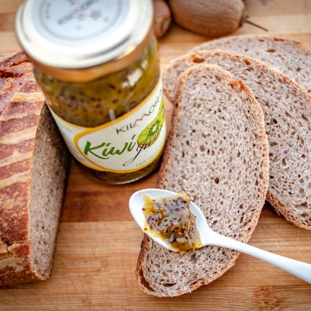 Top shot of a jar of Kilmora Jam with slices of bread and a spoonful of Kiwi Jam on them