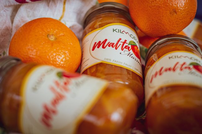 3 jars of Malta Marmalade lying amidst fresh Malta fruits