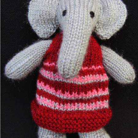 Hand Knit toy of a gray elephant wearing a red frock
