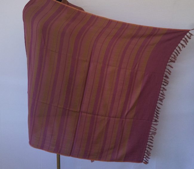 Handwoven pure merino wool shawl from Kilmora with varied vertical stripes in shades of deep rouge and ochre, edged with a thin border of salmon pink.
