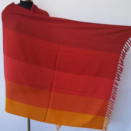 Handwoven pure merino wool shawl from Kilmora with in vertical stripes the colour of our autumn skies. Stripes in shades of carmine, scarlet, red, fiery orange and marigold.