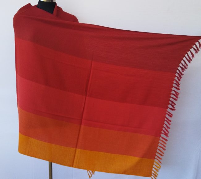 Handwoven pure merino wool shawl from Kilmora with in vertical stripes the colour of our autumn skies. Stripes in shades of carmine, scarlet, red, fiery orange and marigold.
