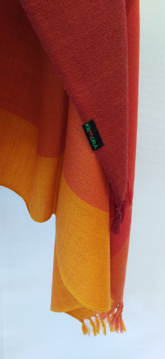 Handwoven pure merino wool shawl from Kilmora with in vertical stripes the colour of our autumn skies. Stripes in shades of carmine, scarlet, red, fiery orange and marigold.