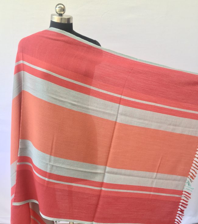 Bold, variegated stripes in tomato, orange, red and grey make up this merino wool shawl from Kilmora
