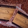 Two packets of Himalayan Red Rice of differing weights on a bed of loose red rice