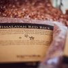 Close up of packet of Himalayan red rice with loose red rice shown in the background
