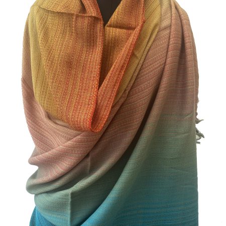 handwoven merino wool shawl in gradation in shades ranging from rust to yellow to peach to pine green