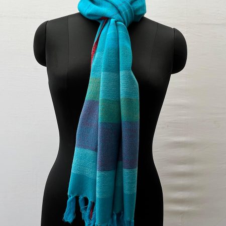 Handwoven merino wool stole in capri blue and thin red selvedge, with end border in vertical stripes of steel blue, ice blue, fern green and navy.