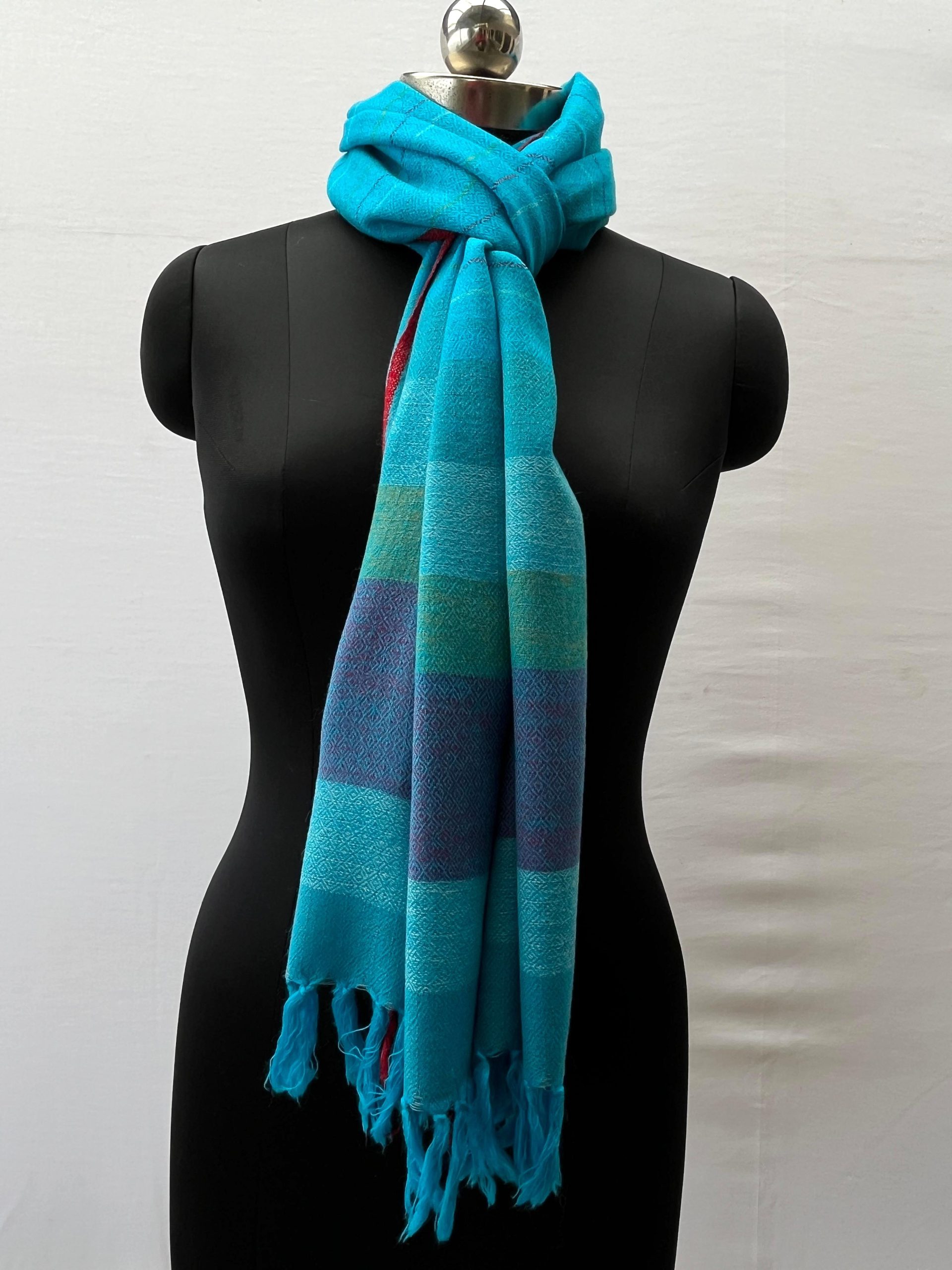 Handwoven merino wool stole in capri blue and thin red selvedge, with end border in vertical stripes of steel blue, ice blue, fern green and navy.