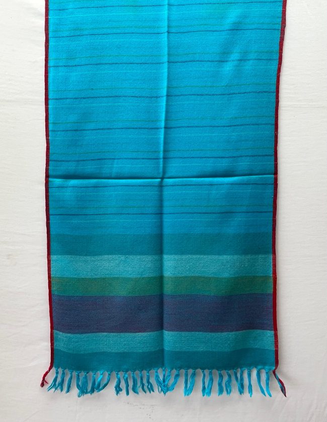 Handwoven merino wool stole in capri blue and thin red selvedge, with end border in vertical stripes of steel blue, ice blue, fern green and navy.