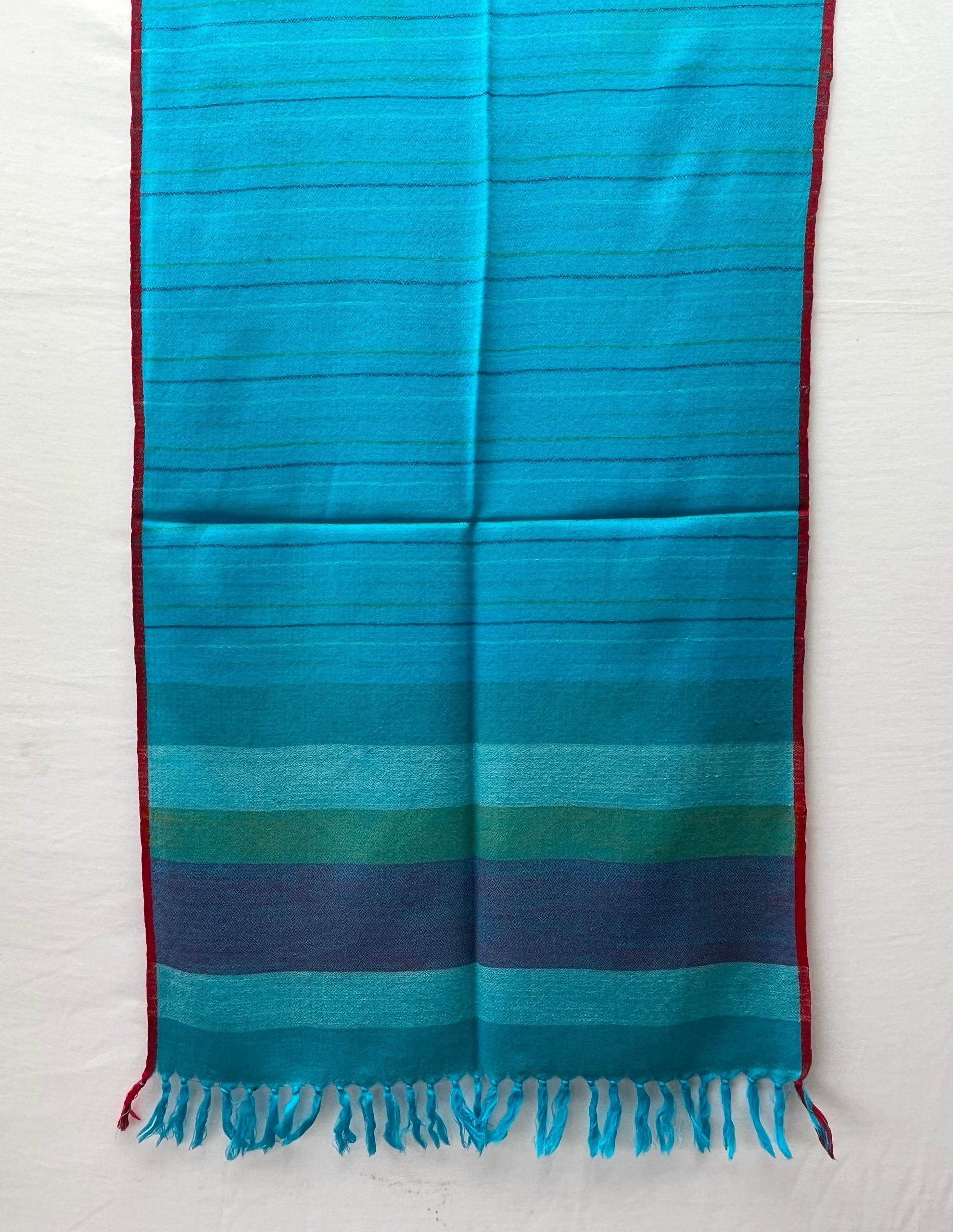 Handwoven merino wool stole in capri blue and thin red selvedge, with end border in vertical stripes of steel blue, ice blue, fern green and navy.