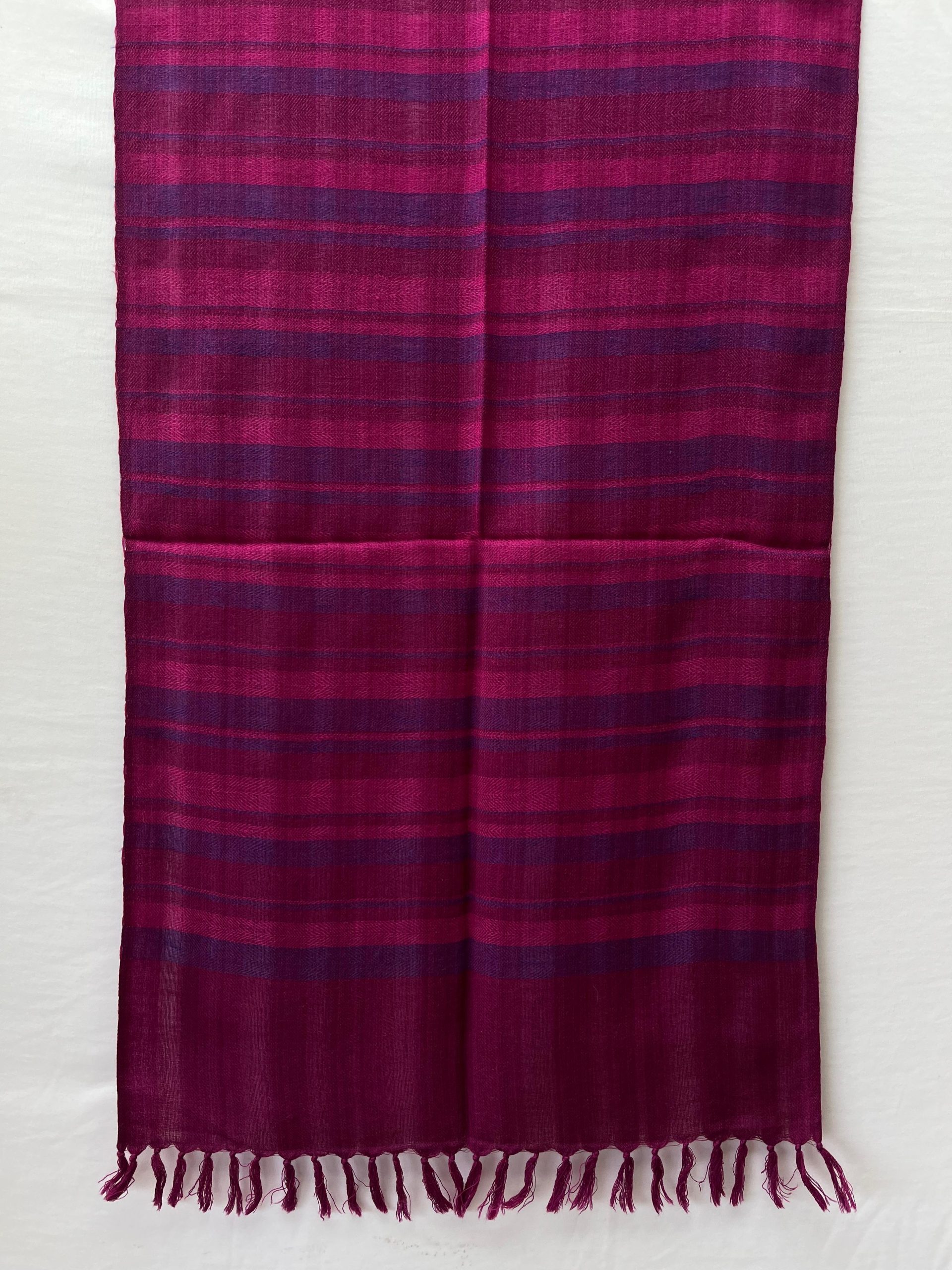 Handwoven merino wool stole woven in vertical stripes of varying widths in shades of fuchsia pink and rich purple