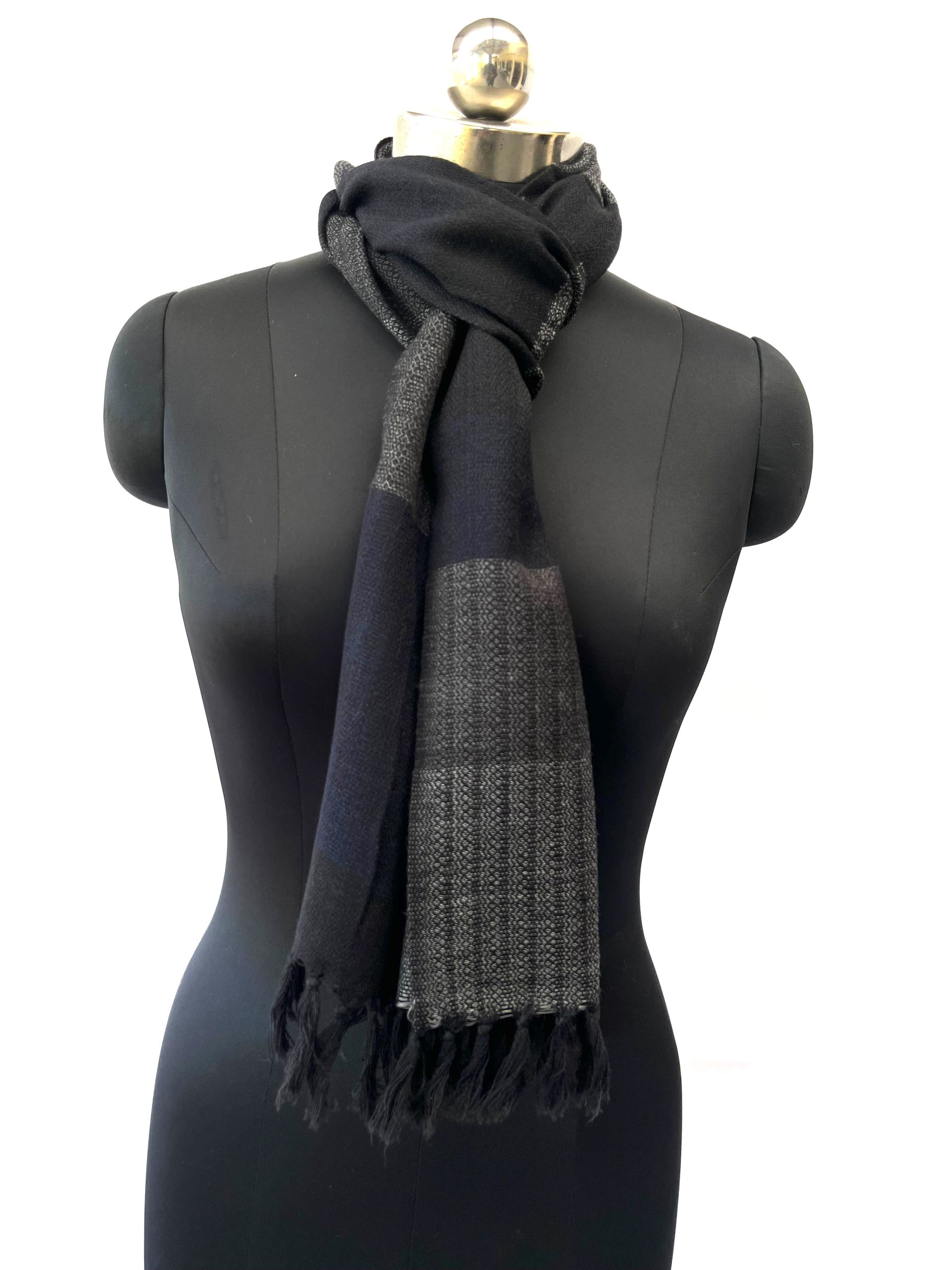 Merino wool scarf knotted on a mannequin, woven in horizontal bands of steel gray, black, lead and pewter