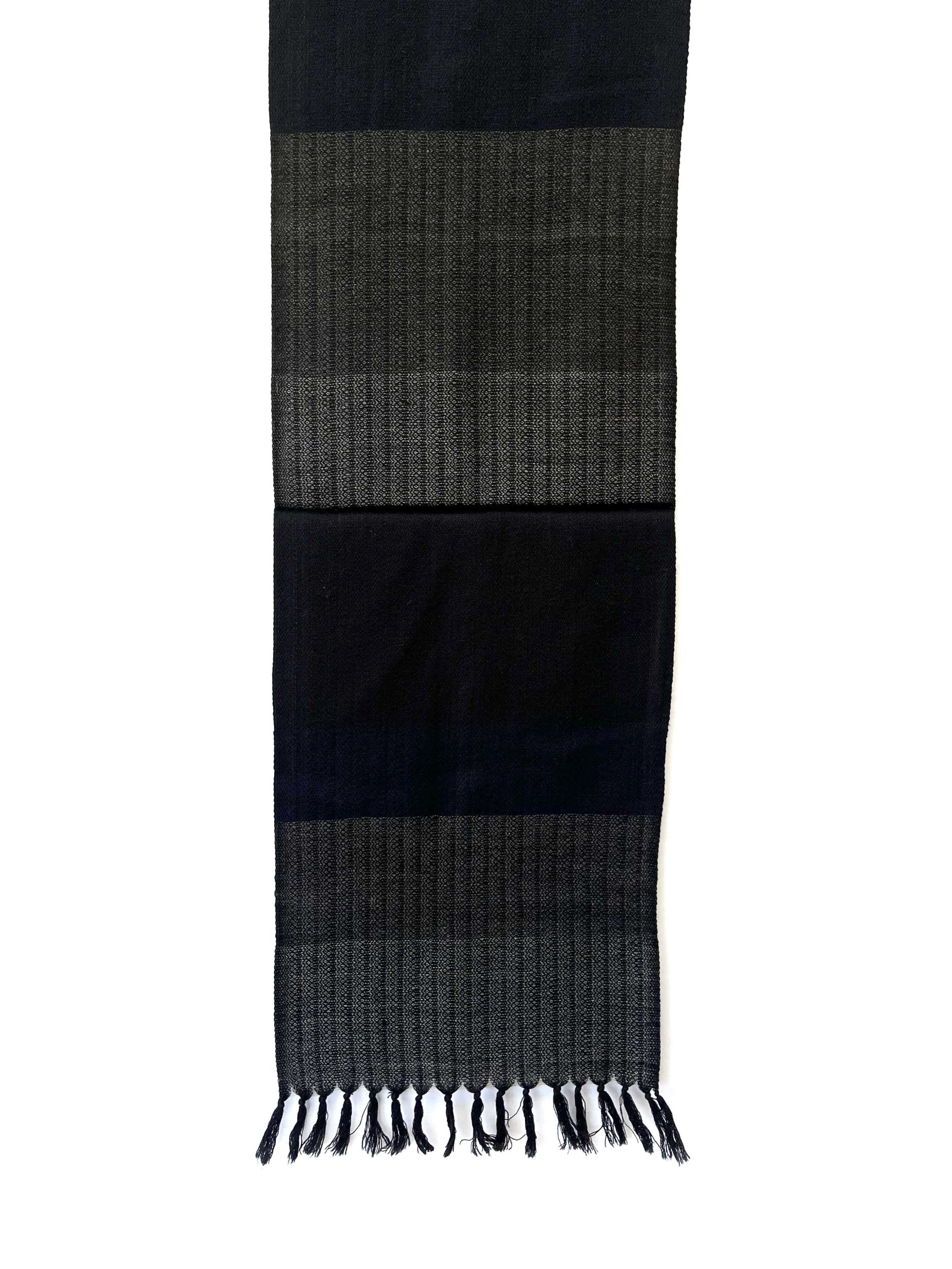 Merino wool scarf knotted on a mannequin, woven in horizontal bands of steel gray, black, lead and pewter