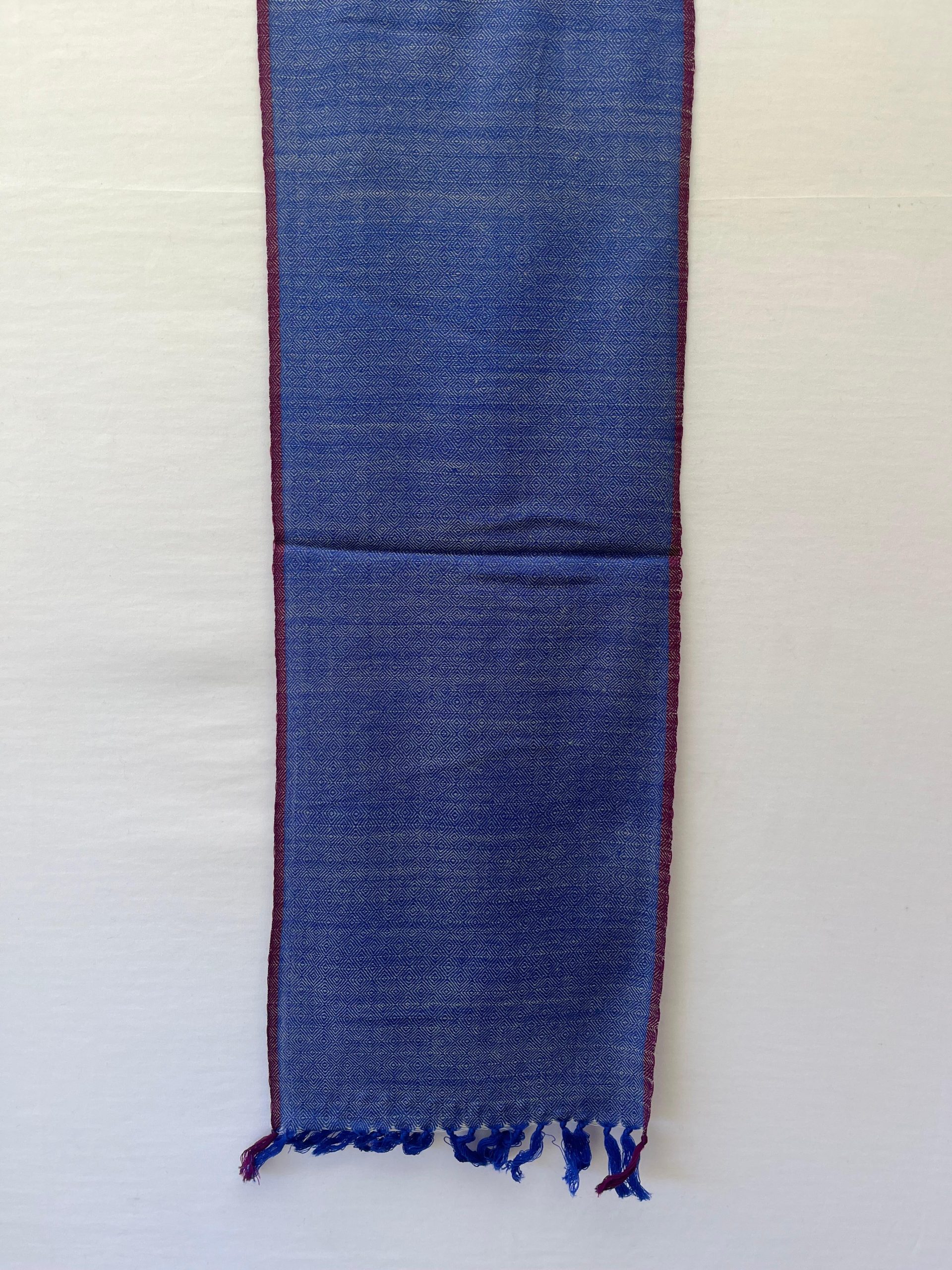 Handwoven merino wool scarf in royal blue diamond pattern with a white weft and thin red selvedge