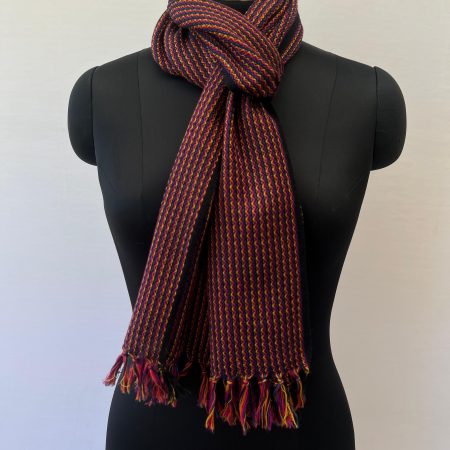 Handwoven merino wool scarf in wavy striped pattern of reds, browns and yellows with a deep brown selvedge