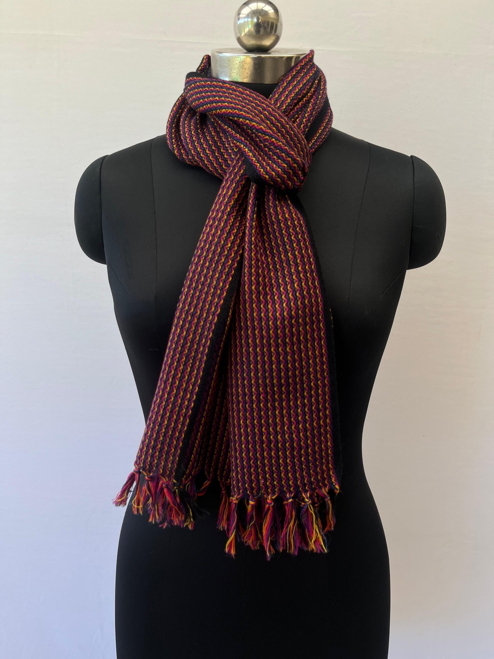 Handwoven merino wool scarf in wavy striped pattern of reds, browns and yellows with a deep brown selvedge