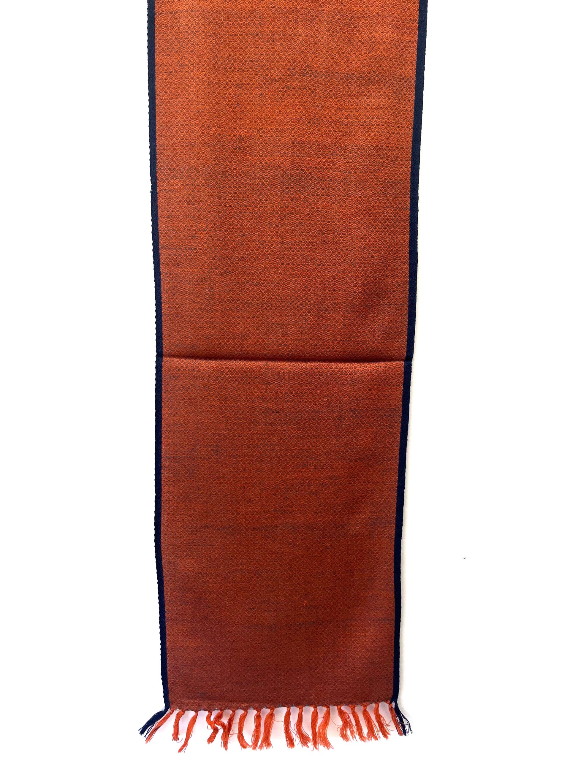 Handwoven merino wool scarf in classic diamond pattern in orange with weft of black and a thin black selvedge