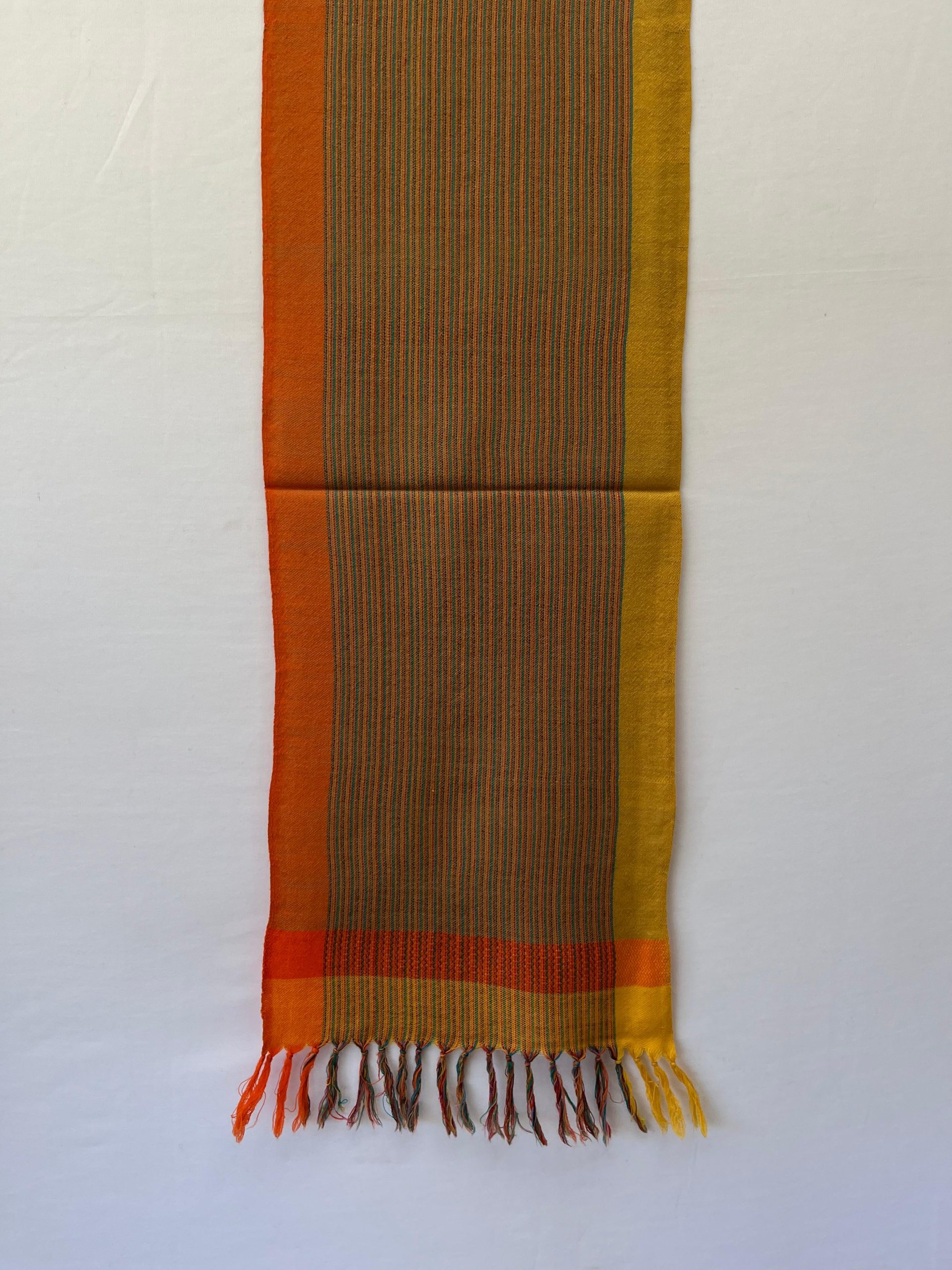 Merino wool scarf with an orange border on one side and an ochre yellow one on the other. With thin pin stripes in deep forest green in between on an ochre yellow background.