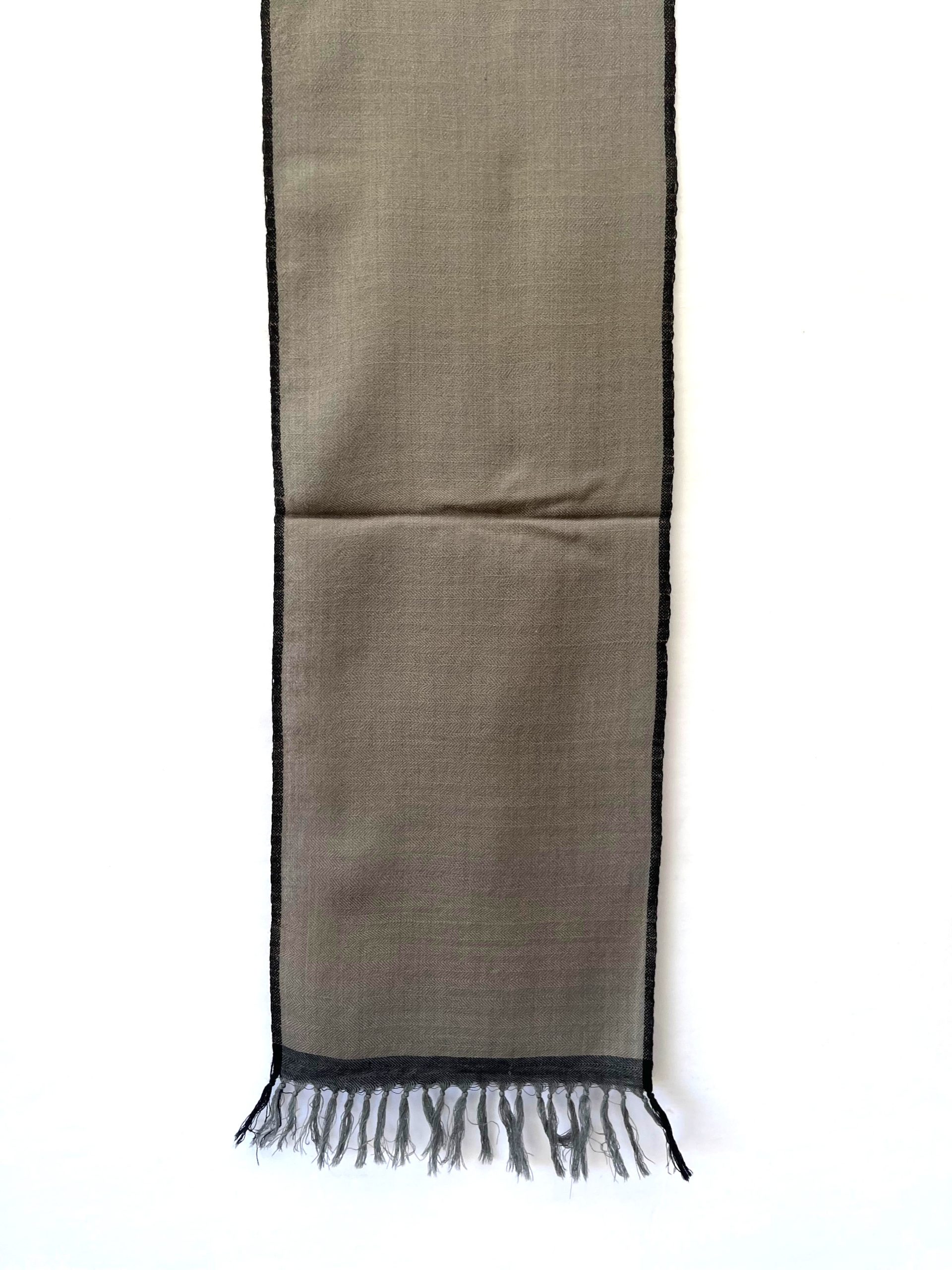 Merino wool handwoven scarf knotted on mannequin. In lead gray with a charcoal selvedge and border.