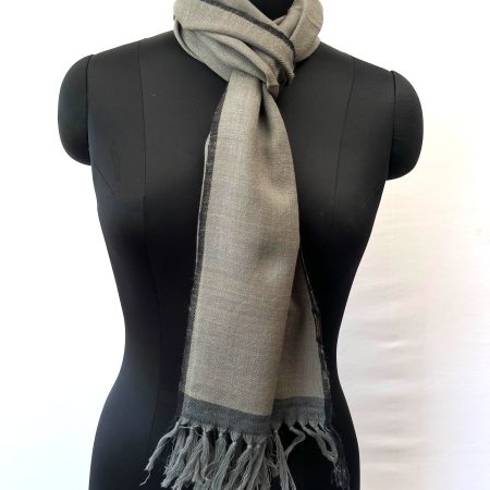 Merino wool handwoven scarf knotted on mannequin. In lead gray with a charcoal selvedge and border.