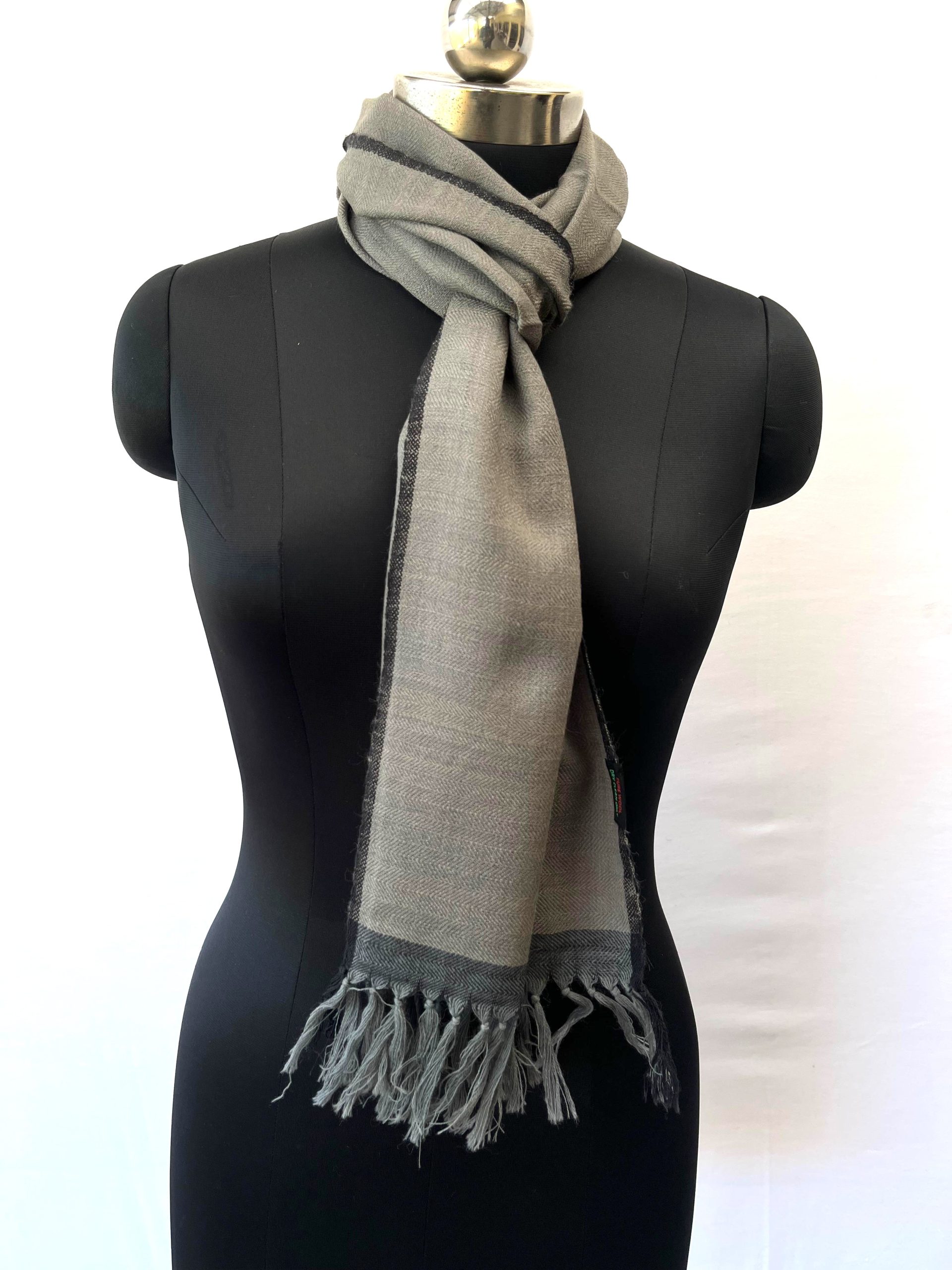 Merino wool handwoven scarf knotted on mannequin. In lead gray with a charcoal selvedge and border.