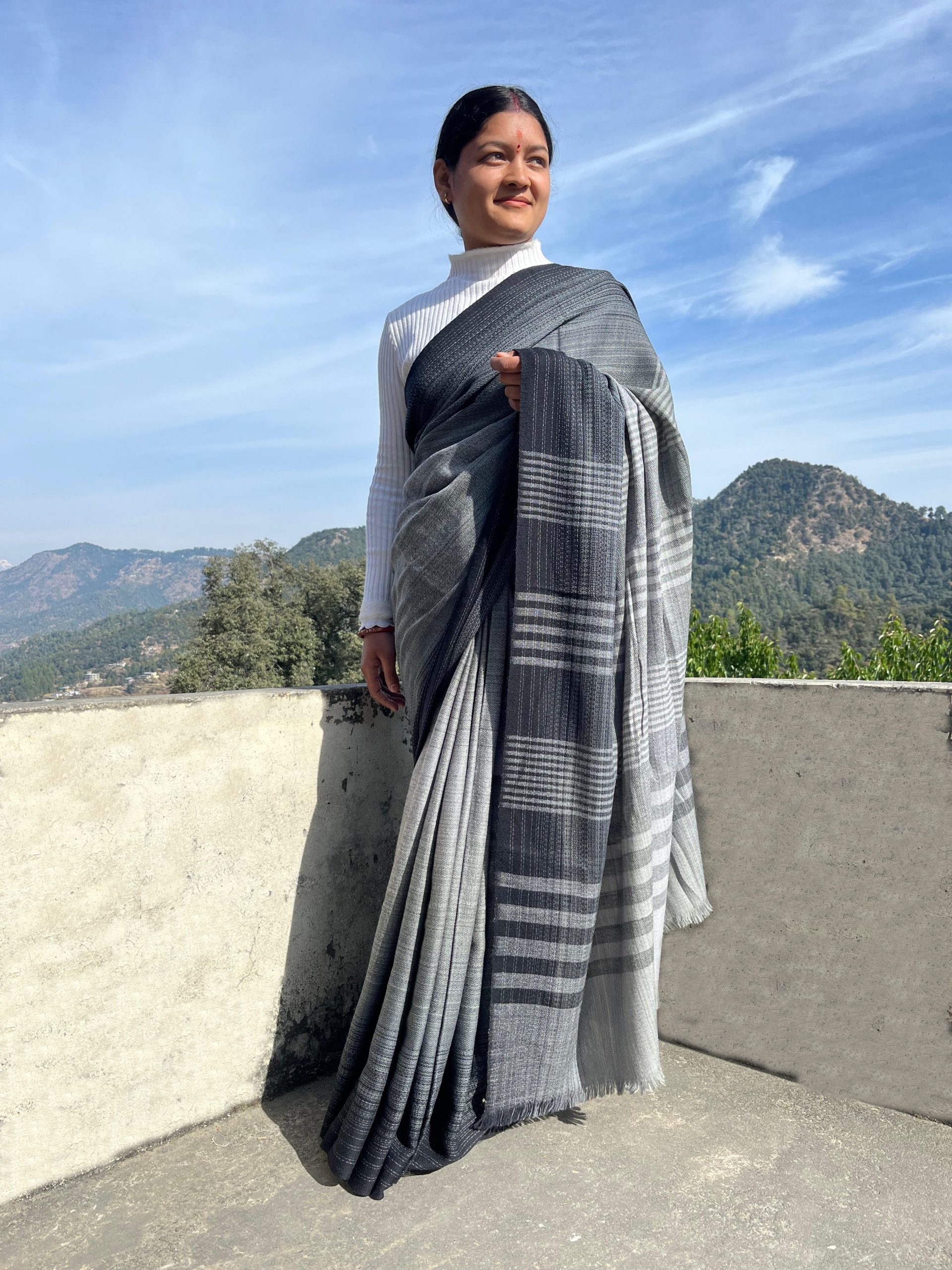 Woman wearing a handwoven merino wool saree in black and white. With the soft gradation making it look charcoal gray.