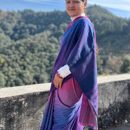 Woman wearing a handwoven merino wool saree in horizontal gradation that starts with a deep plum, to berry blue, to fuchsia and ends with a deep pink.