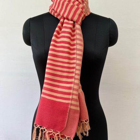 Hand woven cotton stole in a background of blush red with an overlay of tomato red stripes. Knotted on a mannequin.