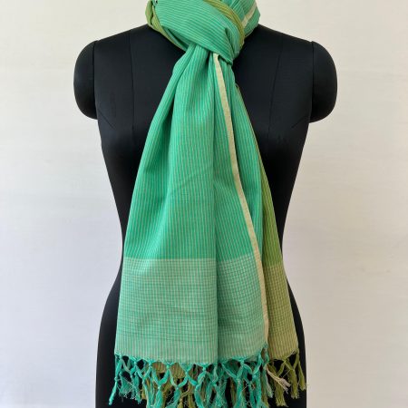 Hand woven cotton stole with two vertical gradations - one in moss green and the other in teal green. With thin vertical stripes woven in as design. Knotted on a mannequin.
