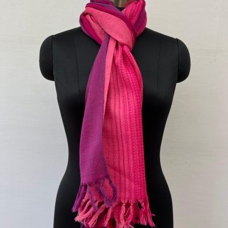 Ombre hand woven merino wool stole in shades of pink - graduating from cerise to hot pink. Knotted on a mannequin.