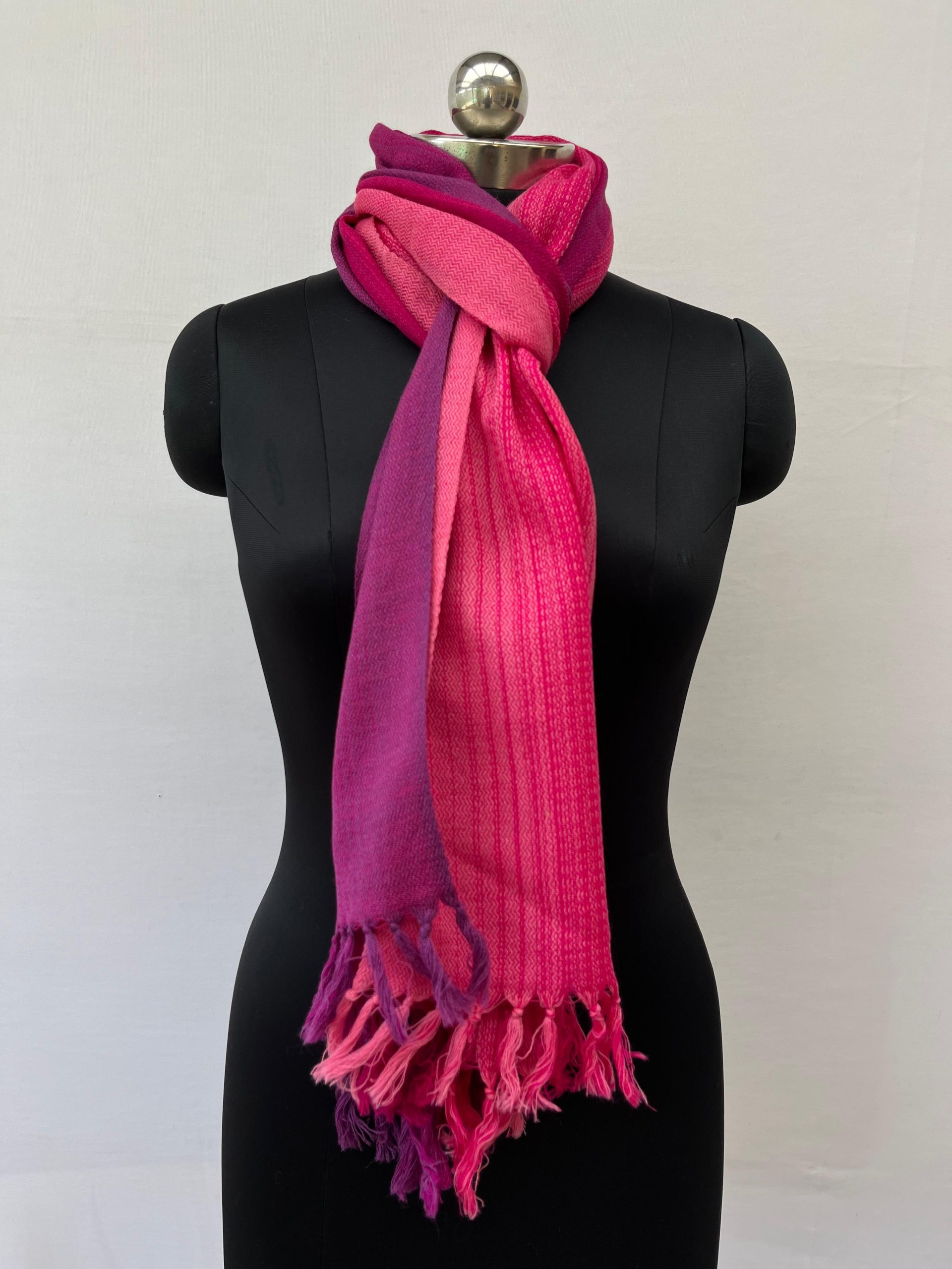 Ombre hand woven merino wool stole in shades of pink - graduating from cerise to hot pink. Knotted on a mannequin.