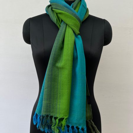 Ombre hand woven merino wool stole in gradation of teal blue, deep cerulean, burdock green and pine. Knotted on a mannequin.