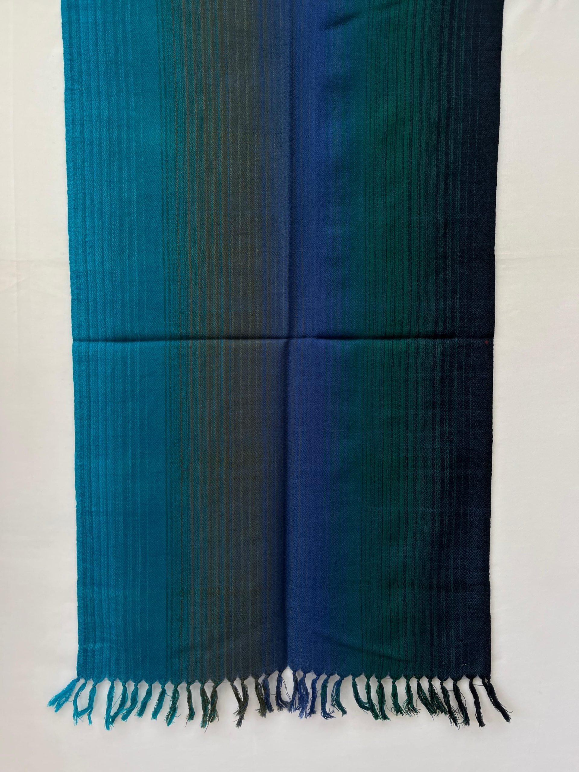 Ombre hand woven merino wool stole that starts with lapis blue, goes into deep pine green, navy and ends with a deep teal.