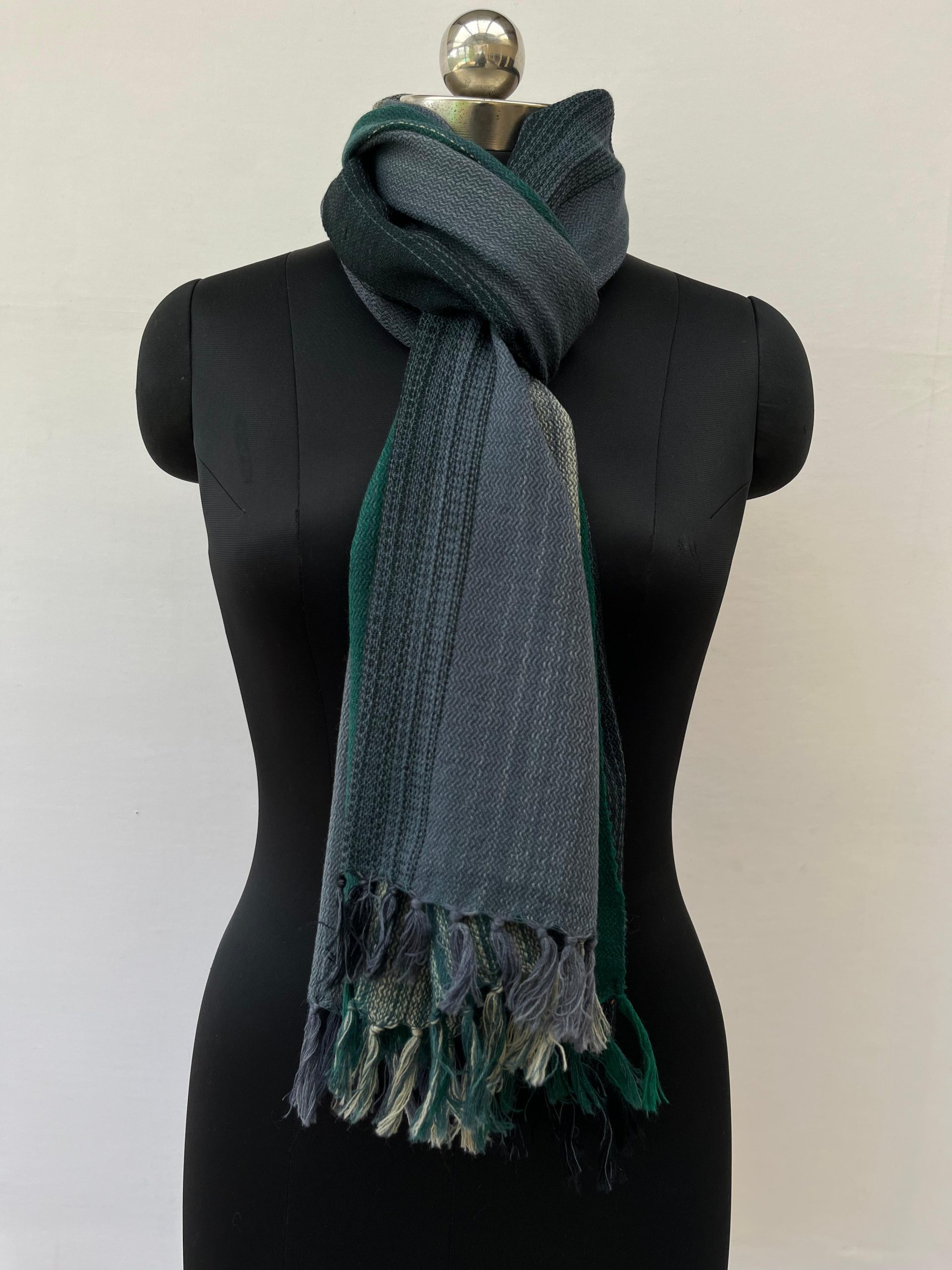Ombre hand woven merino wool stole in deep forest green, silver, and charcoal. Knotted on a mannequin.