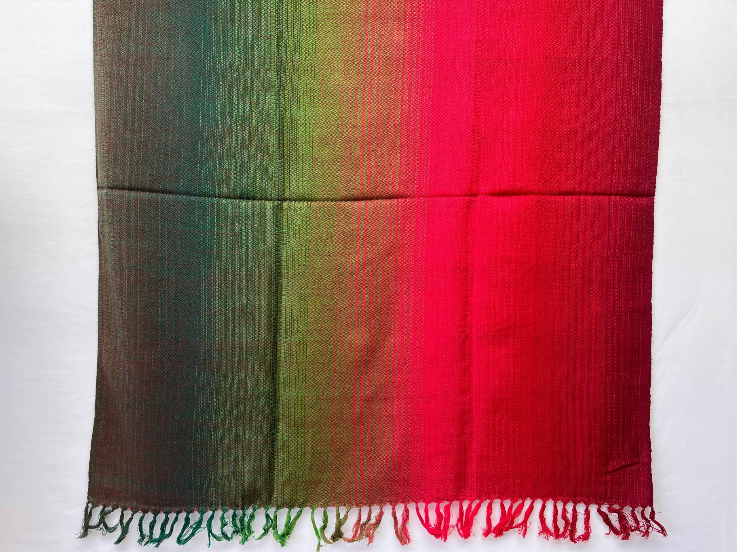 Ombre hand woven merino wool shawl in shades that start with a deep pine green on the left and end with deep maroon on the right.