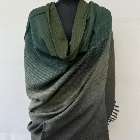 Hand woven merino wool ombre shawl in shades of deep pine green, moss green, solver and pewter. Draped ona mannequin.