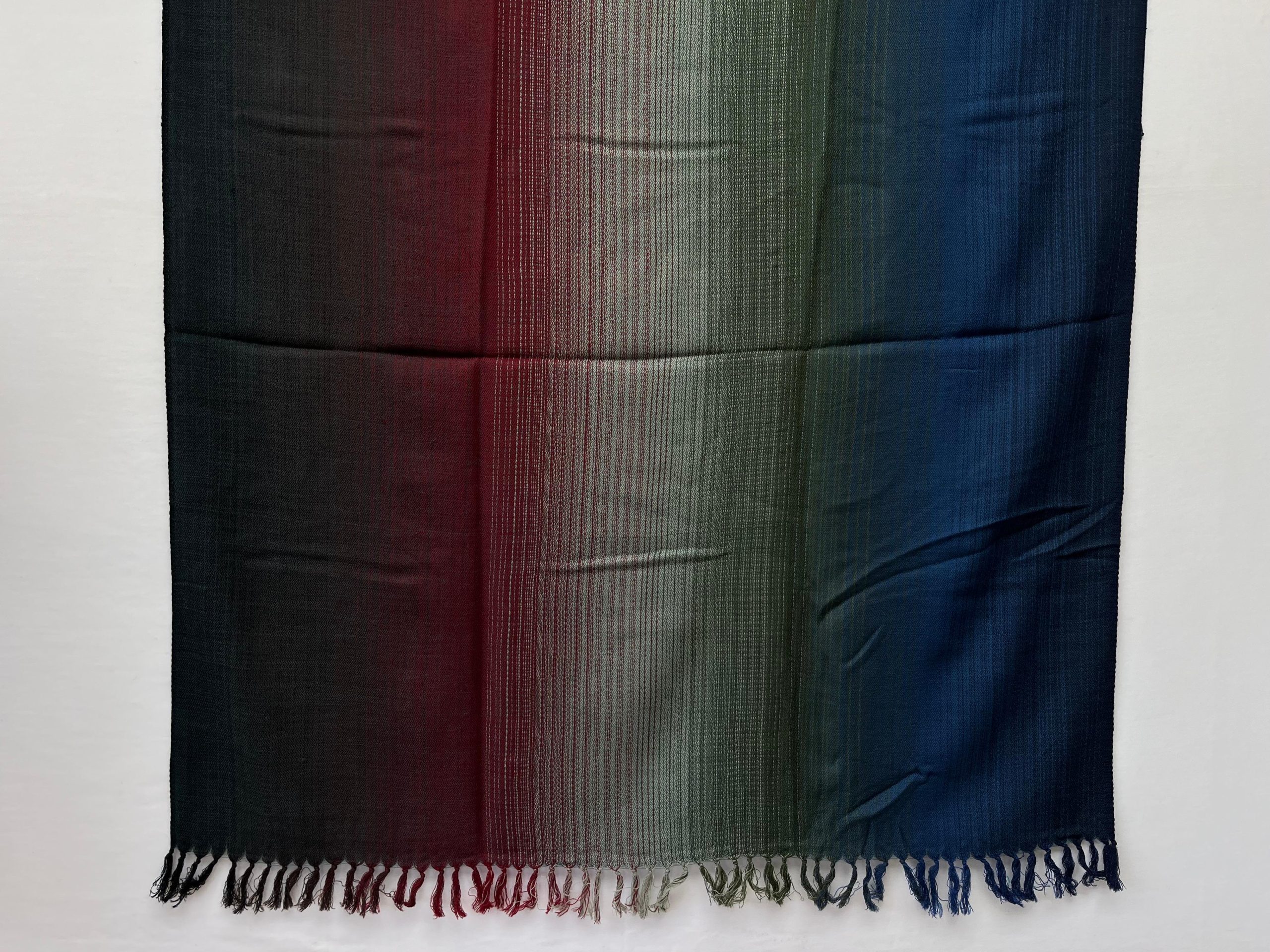 Ombre hand woven merino wool shawl. Starting with deep wine red, graduating to amethyst, silver, graphite and deep blue. Draped on a mannequin.