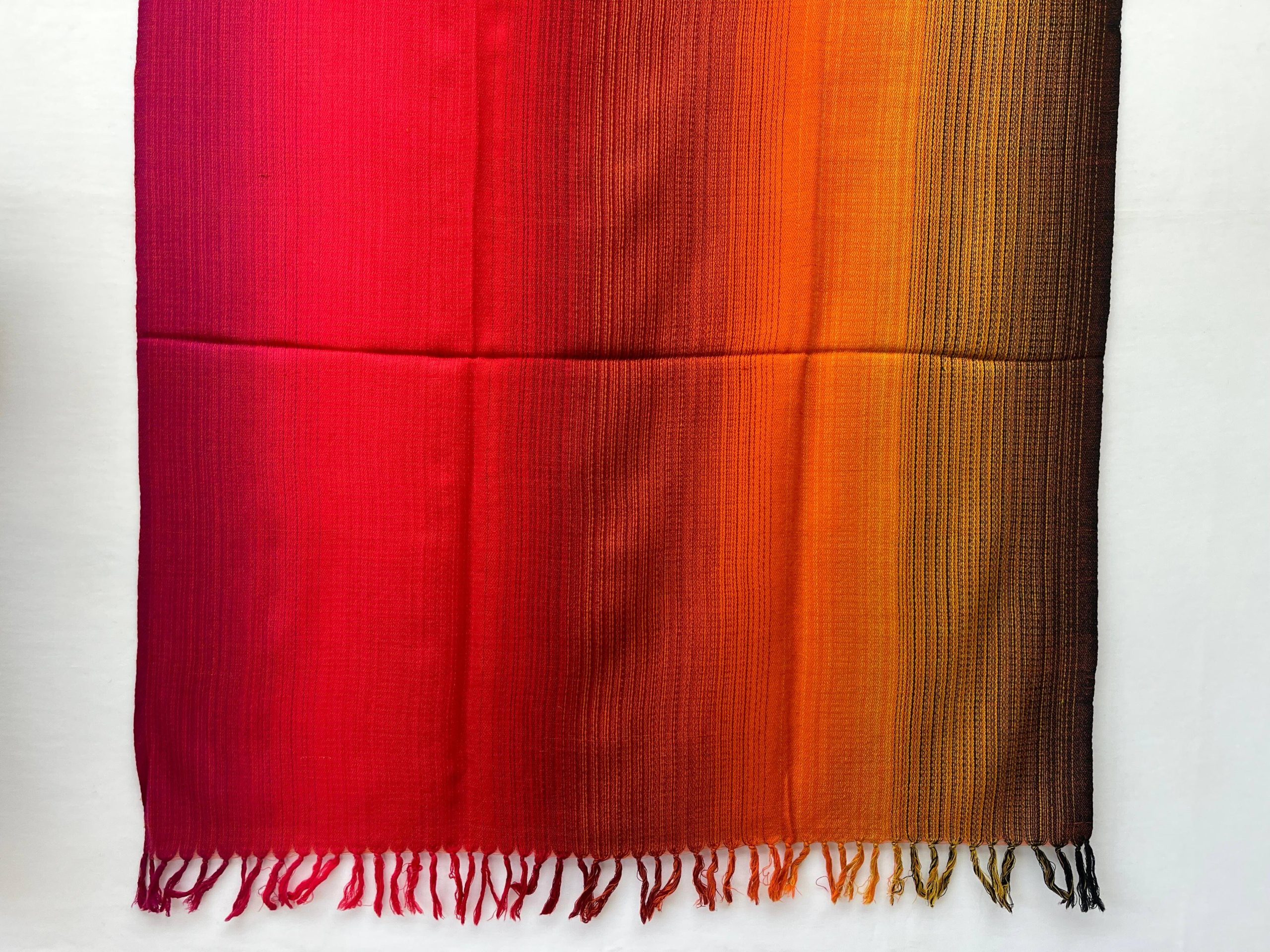 Ombre hand woven merino wool shawl in shades starting with deep red, scarlet, orange and ending with hint of pine green.