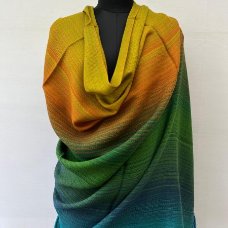 Ombre handwoven merino wool shawl in shades ranging from forest green, pine green, marigold to ochre. Here, draped on a mannequin.