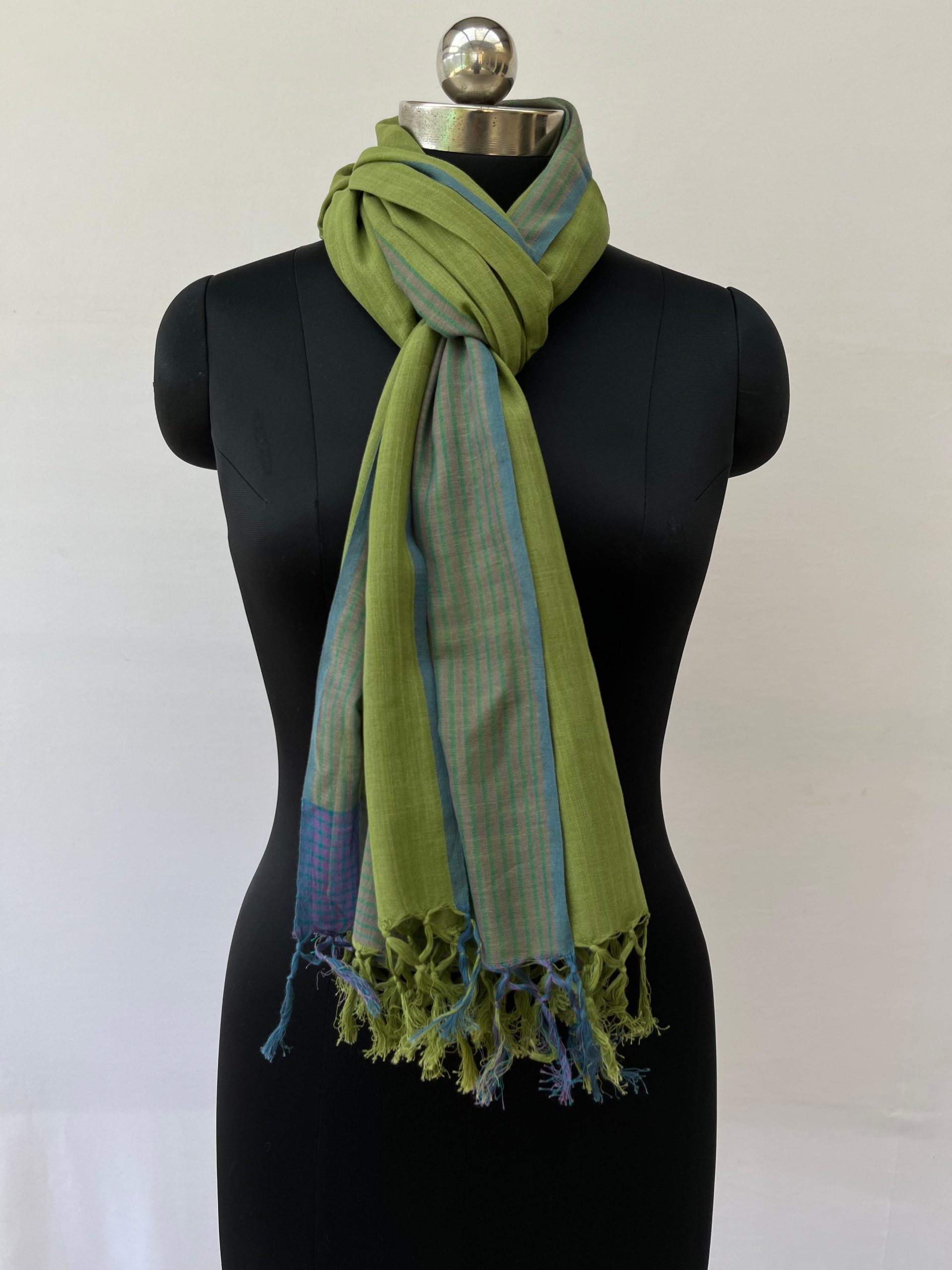 Hand woven cotton stole in spinach green with a navy blue graduated striped border on one vertical end. Knotted on a mannequin.