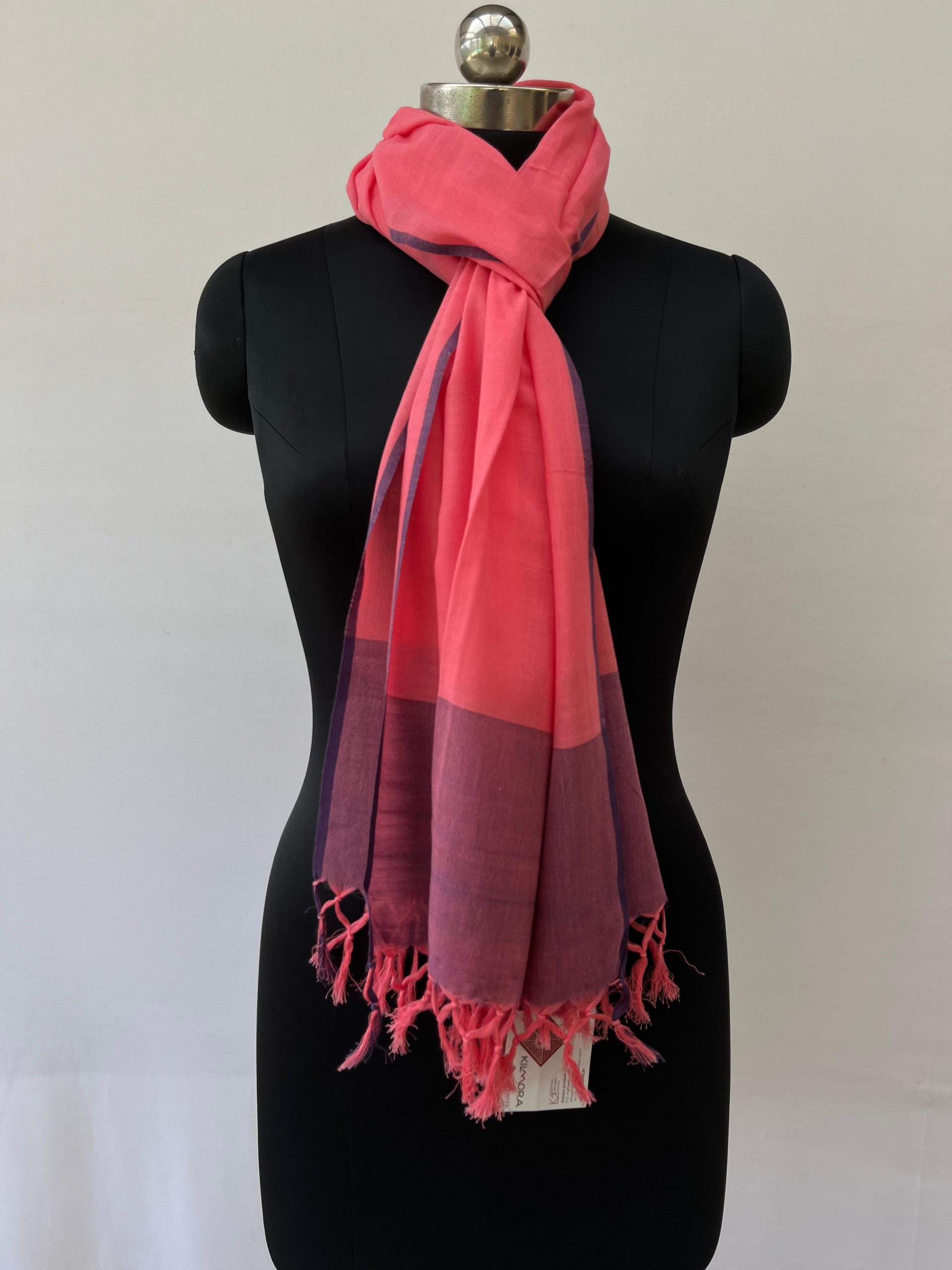 Hand-woven cotton stole in a deep pink, with a thin navy blue edging on both sides and a navy blue border. Knotted on a mannequin.