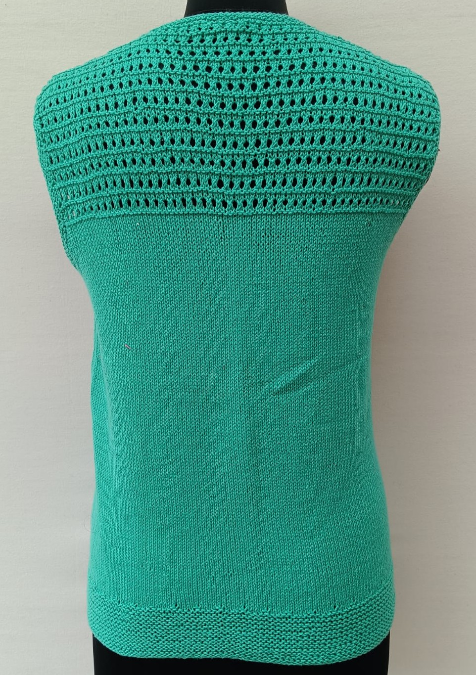 Mannequin is wearing a hand-knit cotton jaali top in mint green, with the detail at the back shown here
