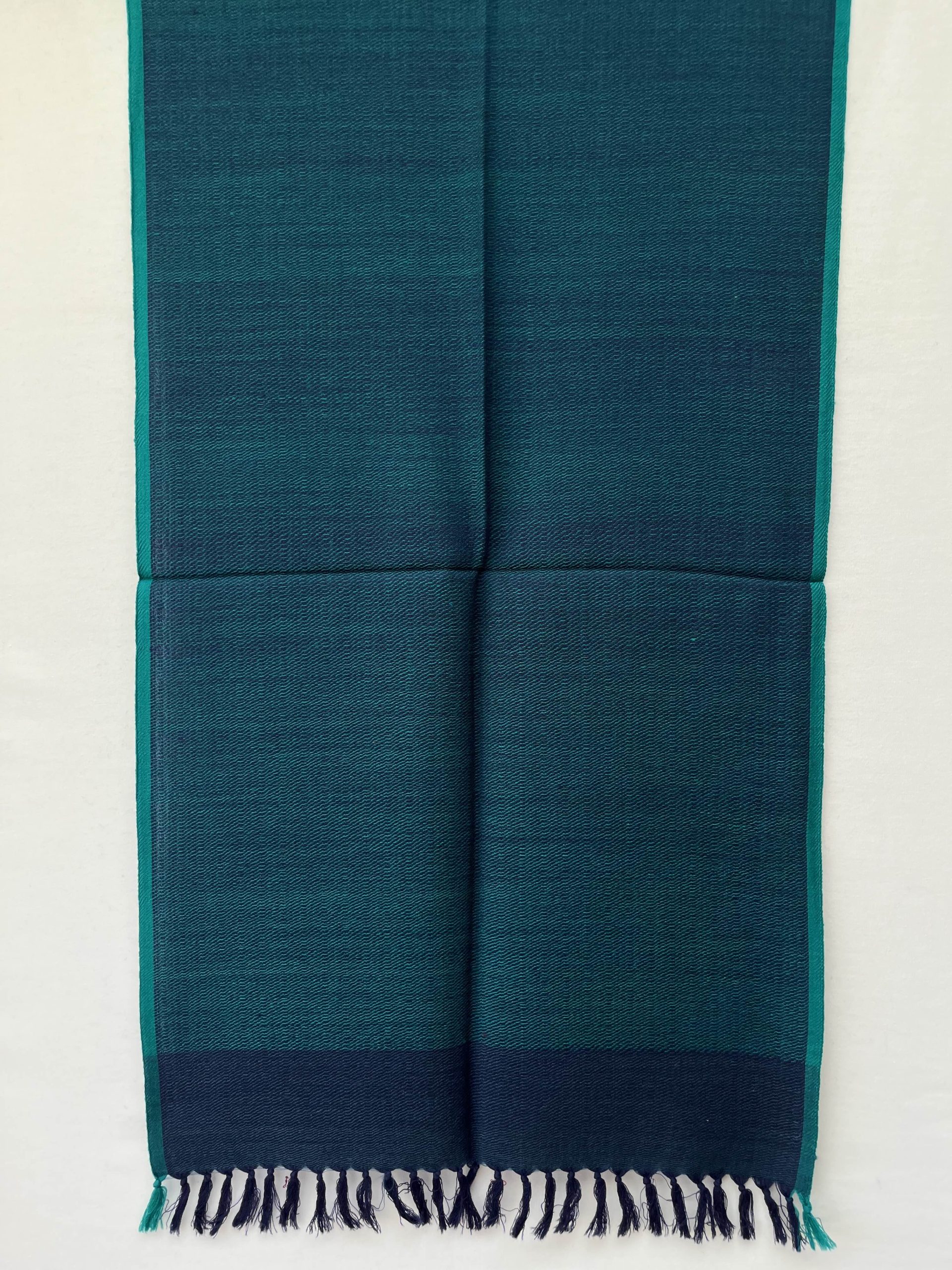 Hand-woven merino wool stole in peacock blue with a teal selvedge.